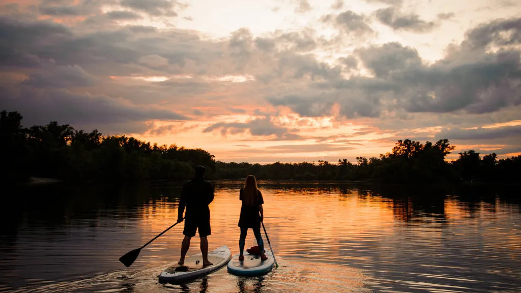 Couple paddle boarding on the lake during the sunset