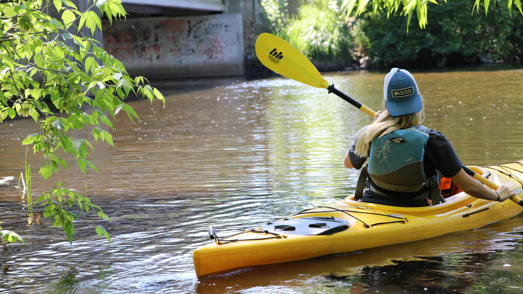 Woman paddling touring kayak down river