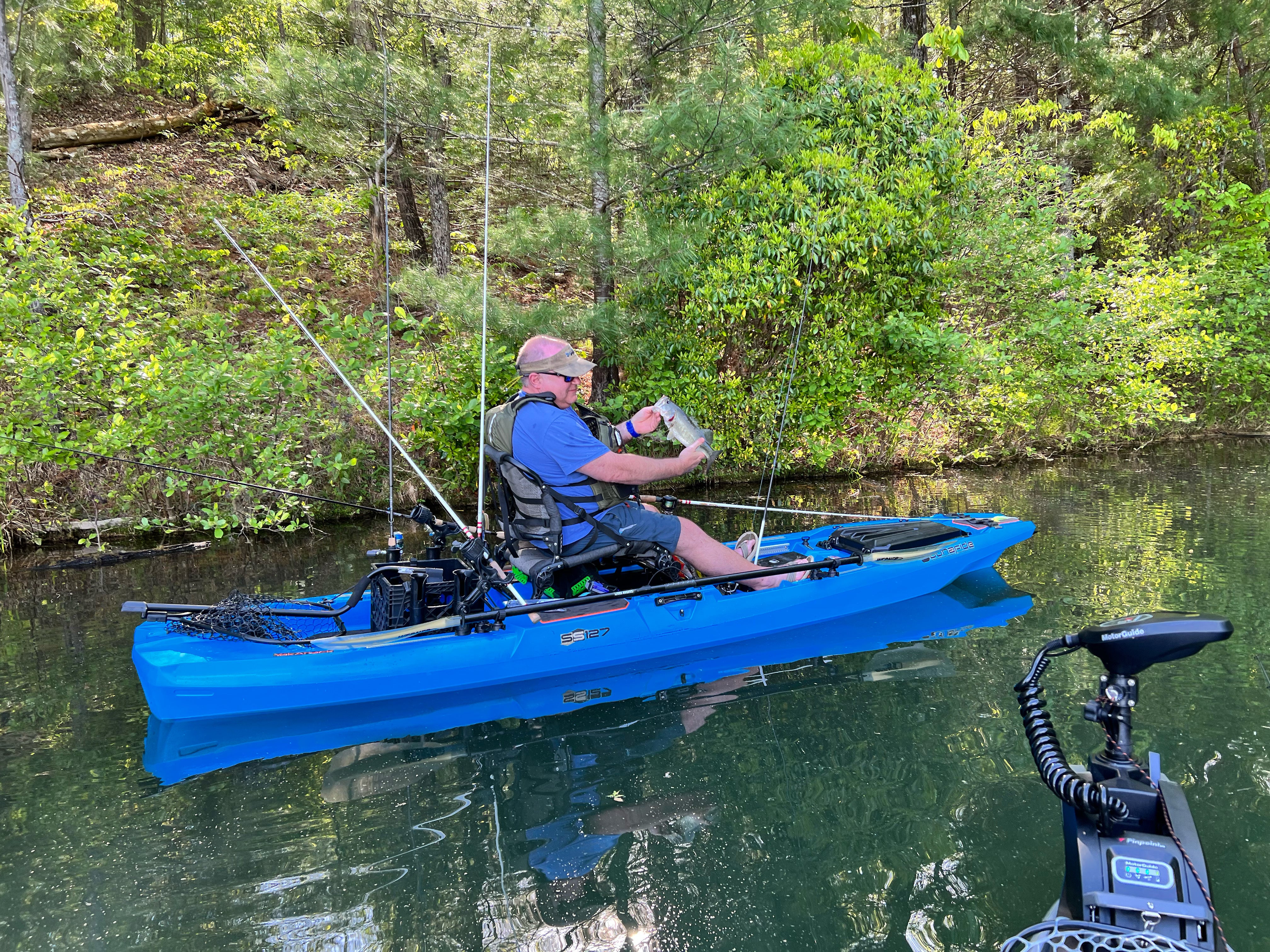 Man holding largemouth bass caught in kayak