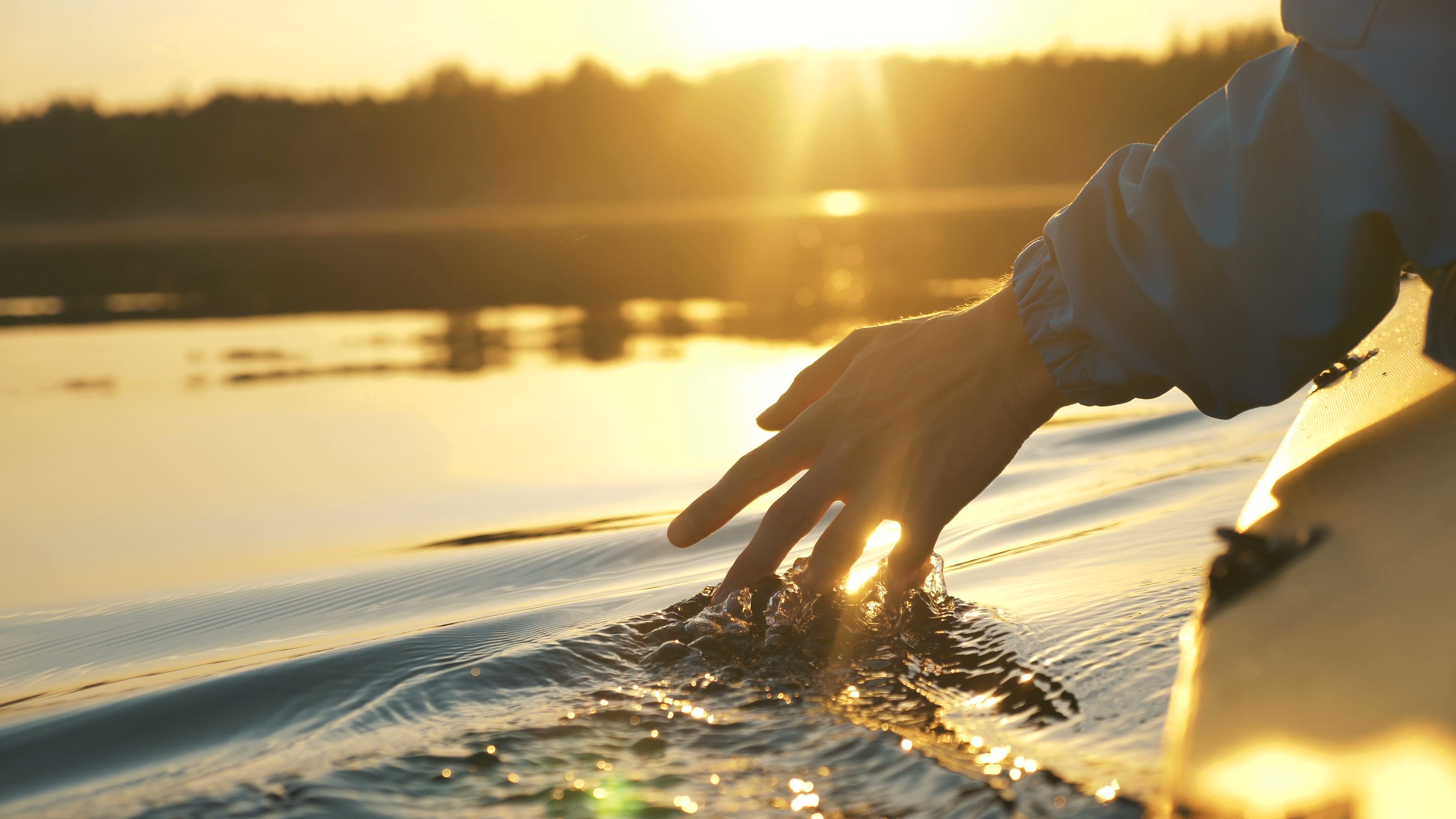 A person floating on their kayak and skimming their hand along the surface of the water