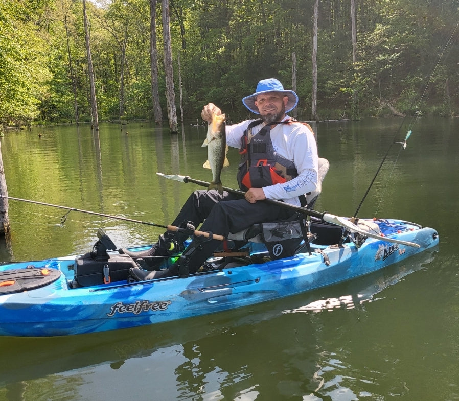 man holding bass in kayak