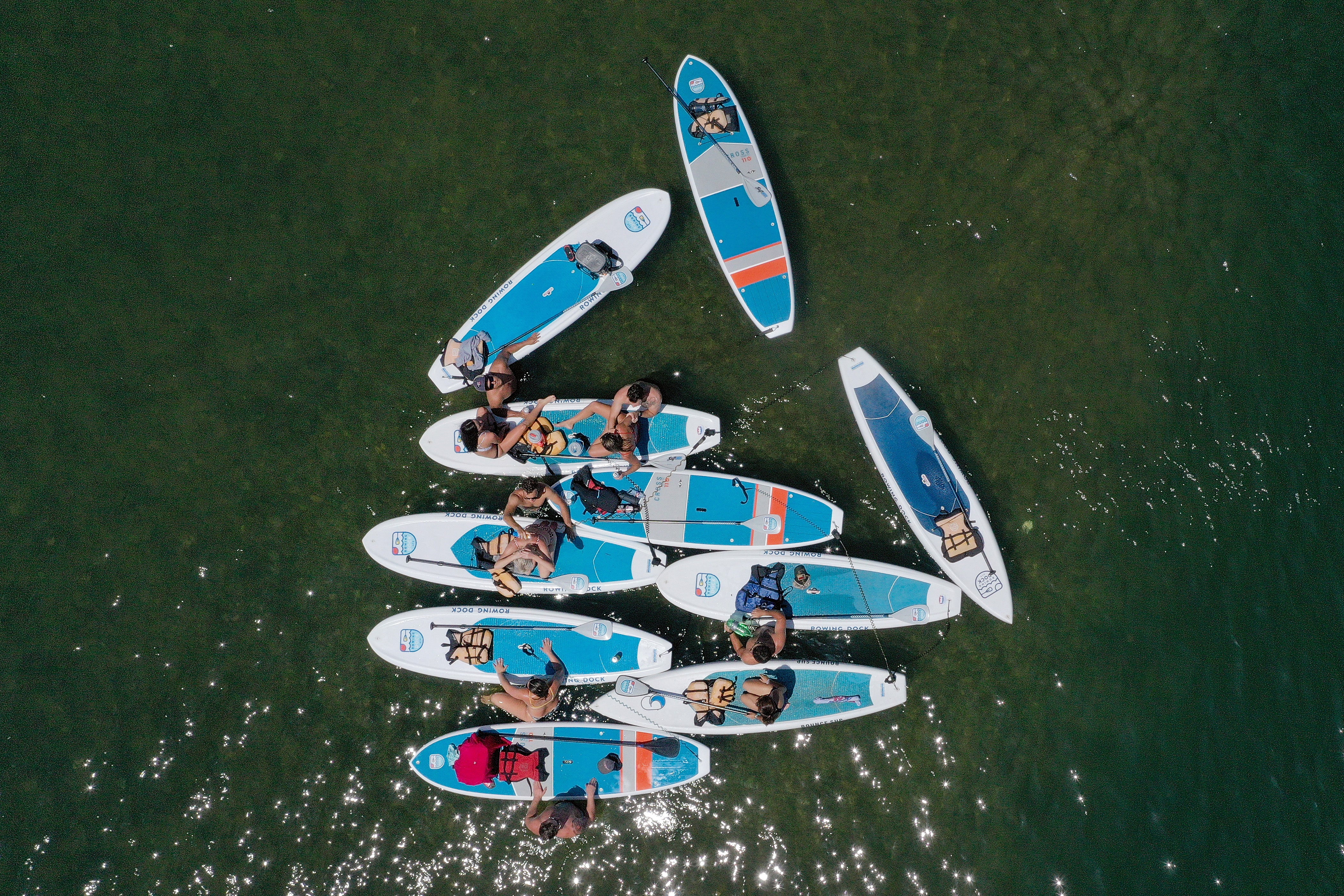 A group of 10 paddle boarders floating in the water