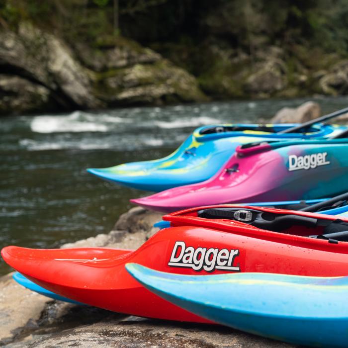 Dagger kayaks lined up on the bank of a river